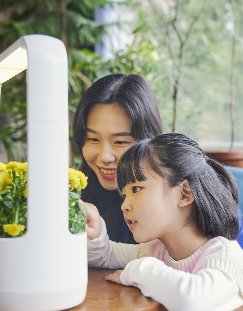 LG 틔운 미니에 식물을 키워 꾸미고 있는 어머니와 아이의 모습