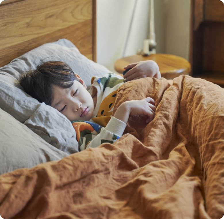 어린 아이가 침대에 누워 자고 있는 모습