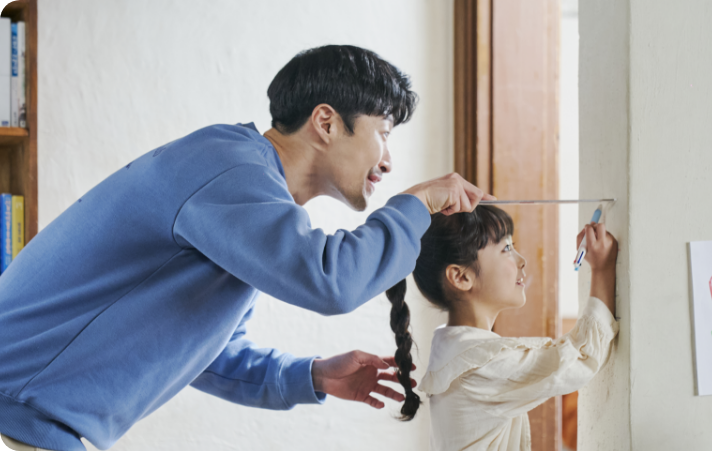 어린 아이와 아버지가 함께 키를 재고 있는 모습