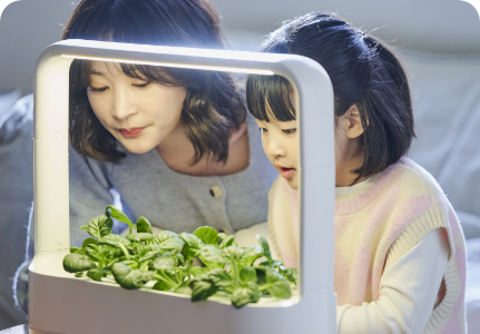 LG 틔운 미니에 자라난 식물을 보고 있는 아이와 어머니 사진